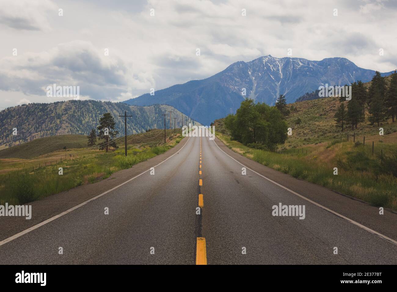 Eine breite offene leere Straße in Richtung der Berge auf dem Highway 3 im Okanagan außerhalb von Cawston, British Columbia. Stockfoto