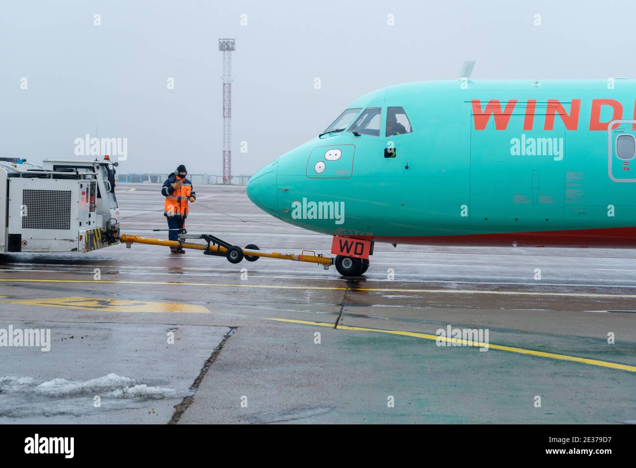 Ukraine, Kiew - 29. Dezember 2020: Das Passagierflugzeug wird auf einer starren Kupplung zum Start geschleppt. Nebliger Flughafen, schlechte Sicht und schlechtes Wetter Stockfoto