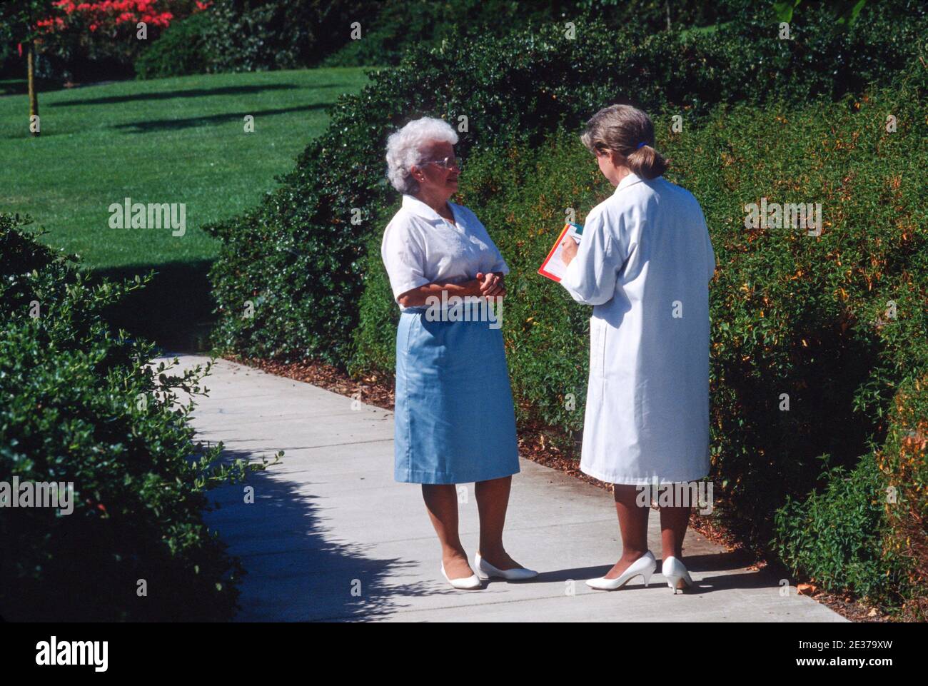 Ärztin mit ihrer älteren Patientin auf dem Krankenhausgelände, CA, USA Stockfoto