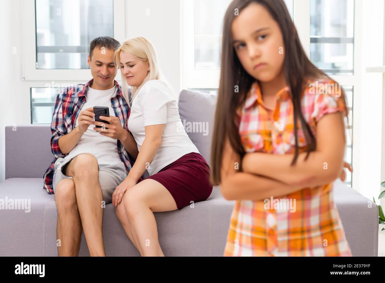 Trauriges Mädchen, das ihre Eltern hört, während es auf dem Sofa sitzt Zu Hause Stockfoto