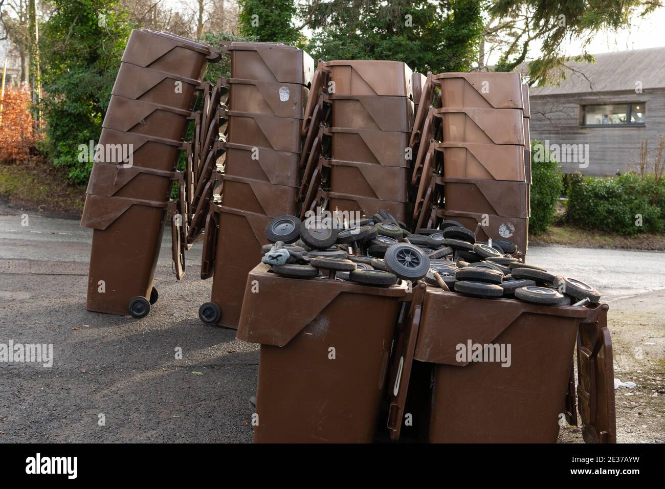 Braune Hausgarten Abfallbehälter an der Seite der Straße für die Sammlung und den Austausch mit neuen (anderes Design) Behälter gestapelt - die Räder sind . . . Stockfoto