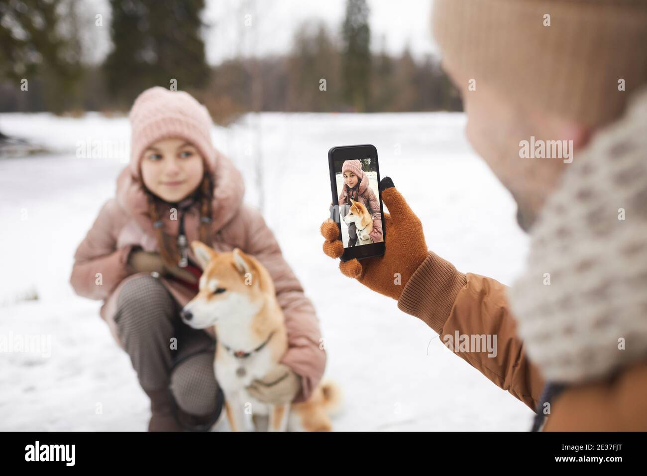 Porträt des Vaters Foto von niedlichen Tochter mit Hund beim Genießen Spaziergang im Freien zusammen im Winterwald, Fokus auf Smartphone-Bildschirm, kopieren Spa Stockfoto Porträt des Vaters Foto von niedlichen Tochter mit Hund beim Genießen Spaziergang im Freien zusammen im Winterwald, Fokus auf Smartphone-Bildschirm, kopieren Spa Stockfoto