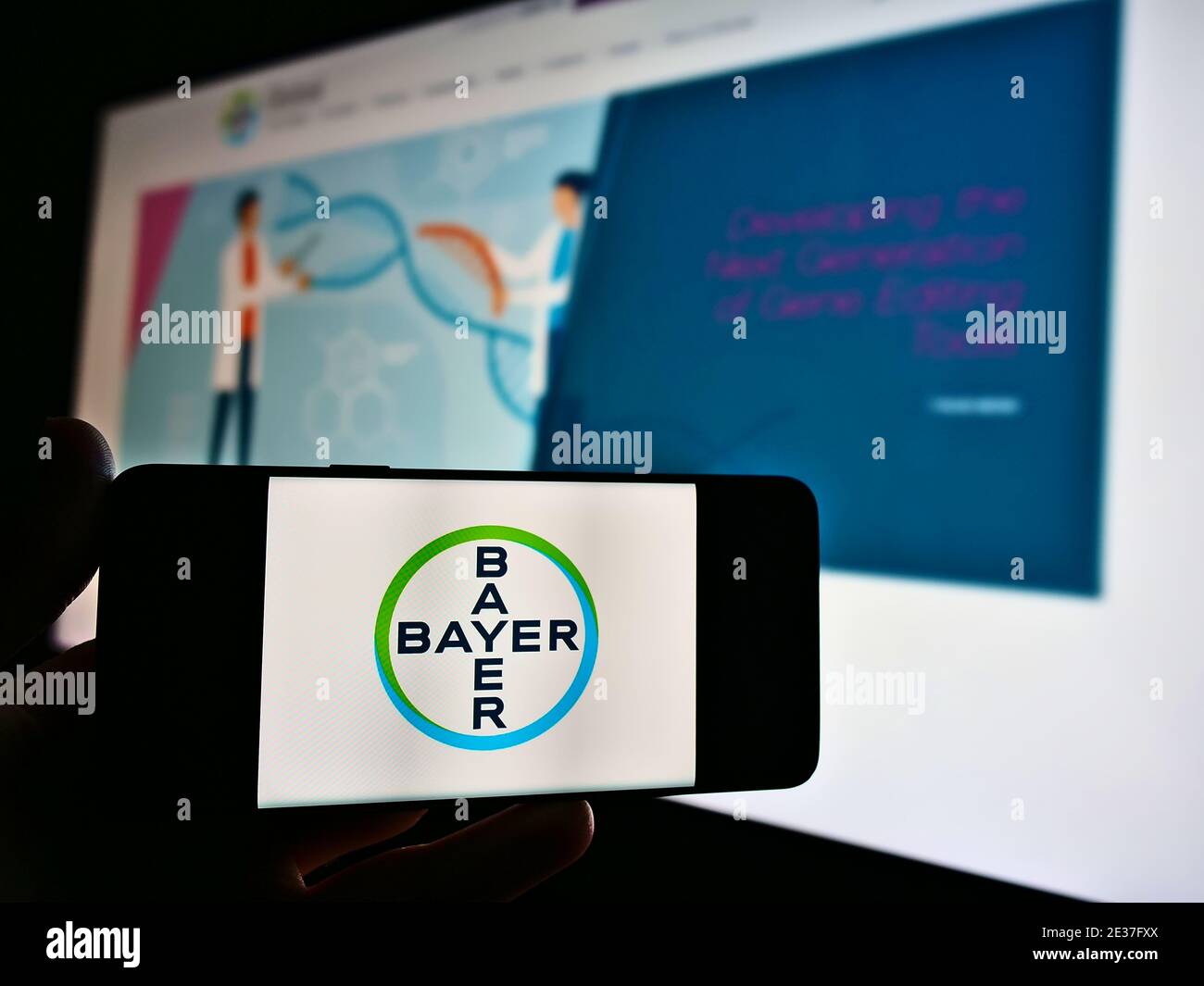 Person mit Smartphone mit Logo des deutschen Unternehmens Bayer AG, einem multinationalen Pharmaunternehmen. Konzentrieren Sie sich auf den Bildschirm des Mobiltelefons. Stockfoto