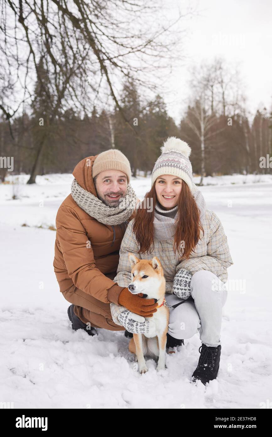 Vertikale voller Länge Porträt von glücklich erwachsenen Paar posiert mit Hund im Freien und Blick auf die Kamera während des Winterspaziergangs Gemeinsam Stockfoto Vertikale voller Länge Porträt von glücklich erwachsenen Paar posiert mit Hund im Freien und Blick auf die Kamera während des Winterspaziergangs Gemeinsam Stockfoto