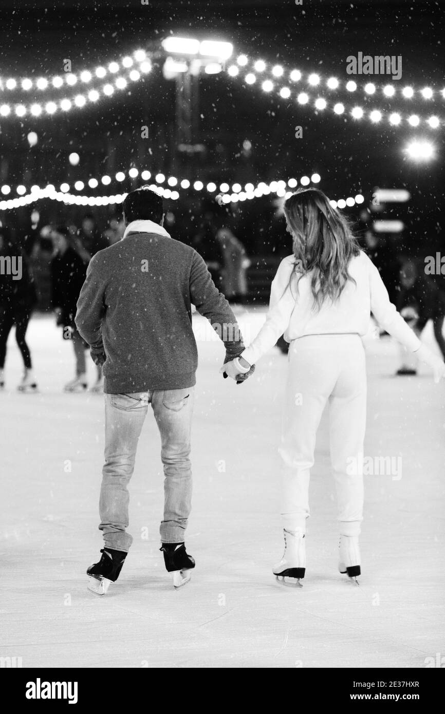 Ein paar Liebhaber halten die Hände auf der Eisbahn im Freien in der Winterzeit. Weihnachten Sport Freizeit Urlaub Stockfoto