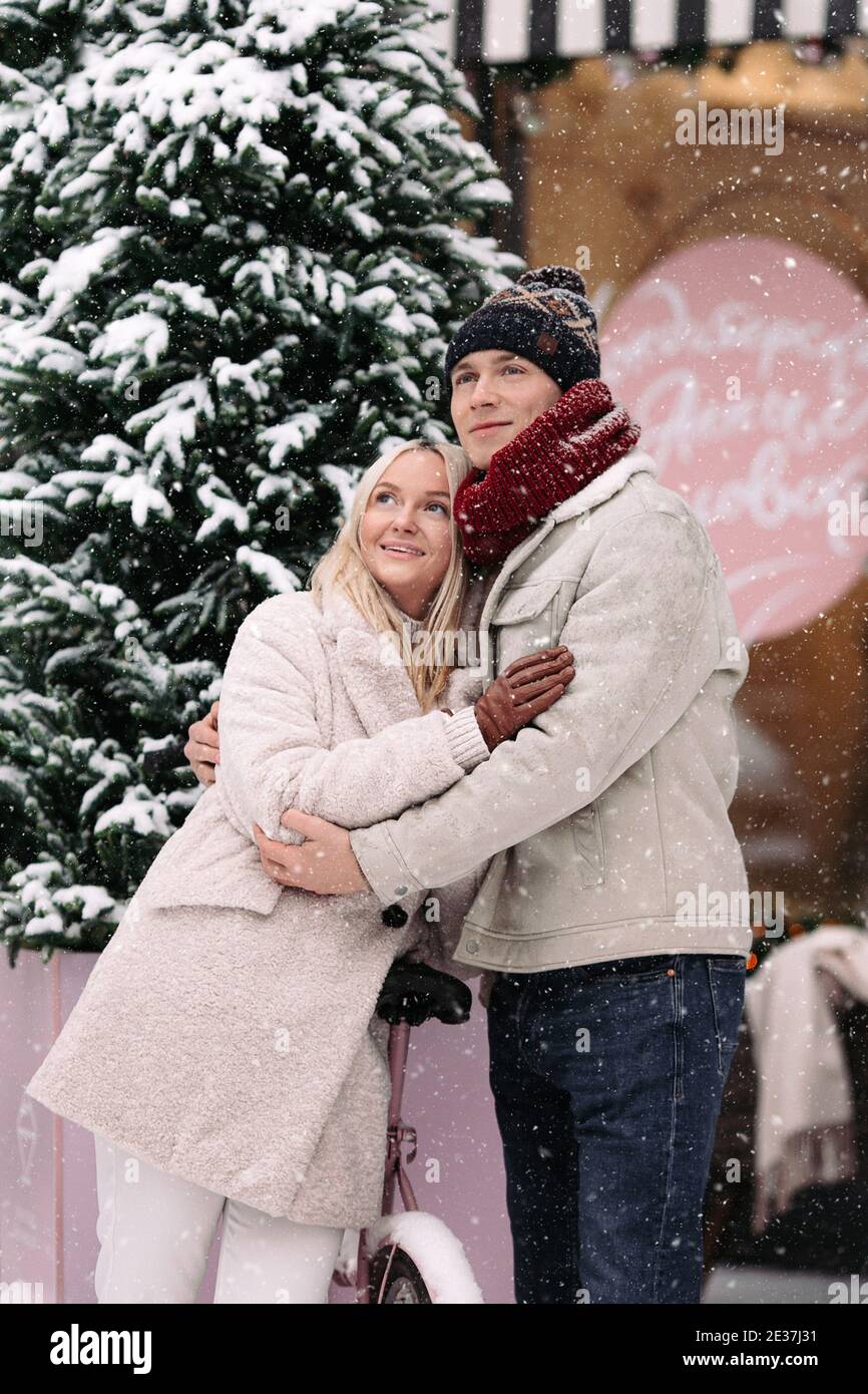Stilvolle romantische Paar umarmen, Spaß im Winter stehen von alten rosa Fahrrad während Schneefall Stockfoto