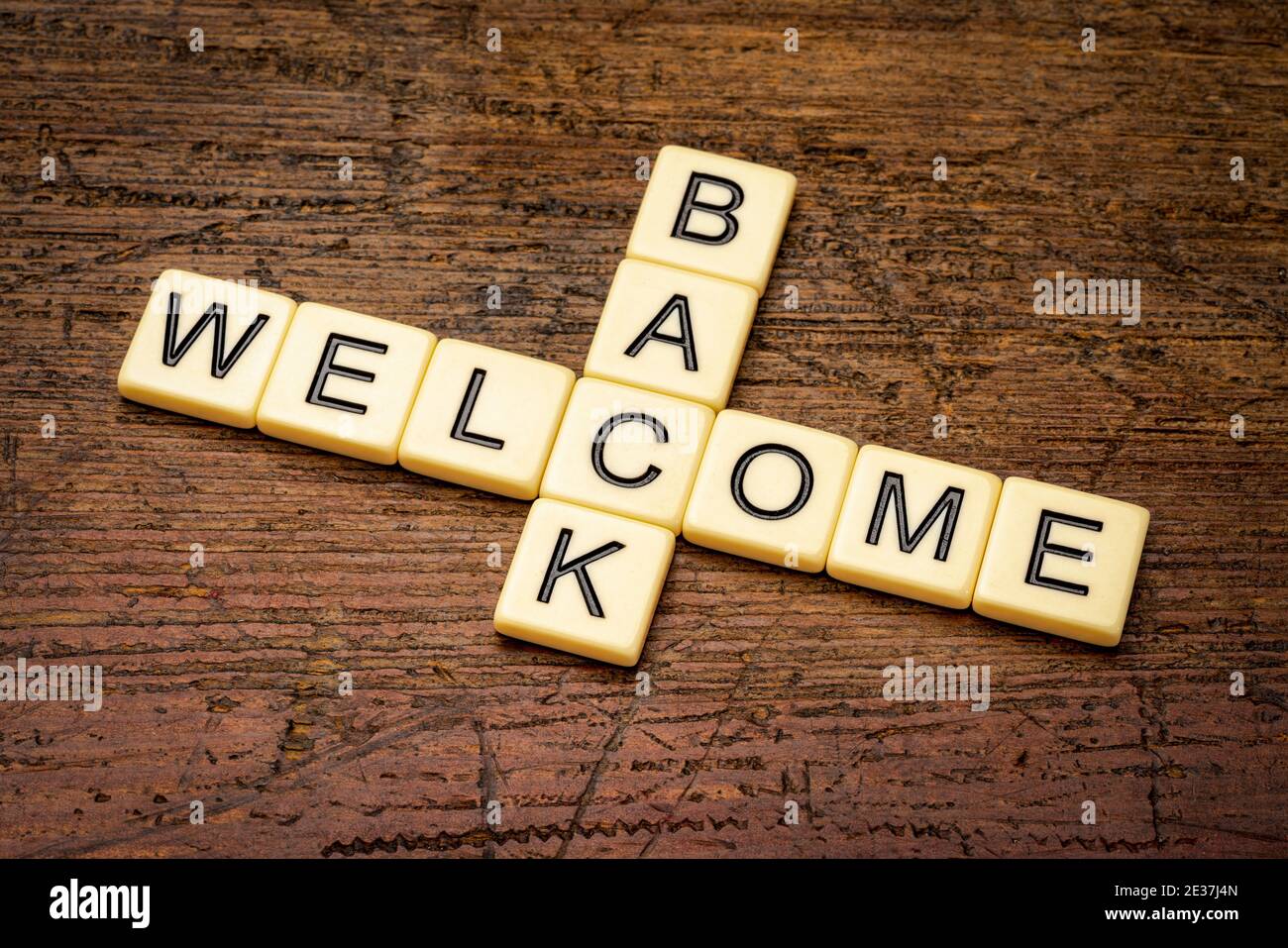 Willkommen zurück Kreuzworträtsel in Elfenbein Buchstaben Fliesen gegen rustikales Holz, Geschäft Wiedereröffnung Konzept, Stockfoto