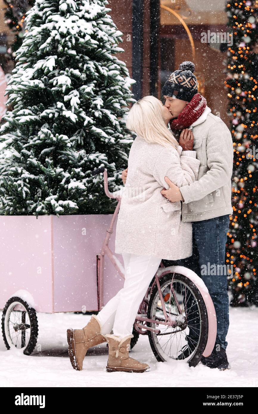 Romantisches Paar küssen, umarmen, Spaß im Winter, stehen von alten rosa Fahrrad während Schneefall Stockfoto