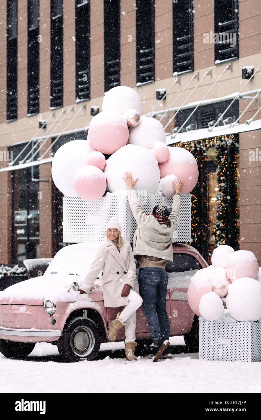Romantisches Paar Spaß im Winter stehen bei der alten Retro rosa Auto bei Schneefall Stockfoto