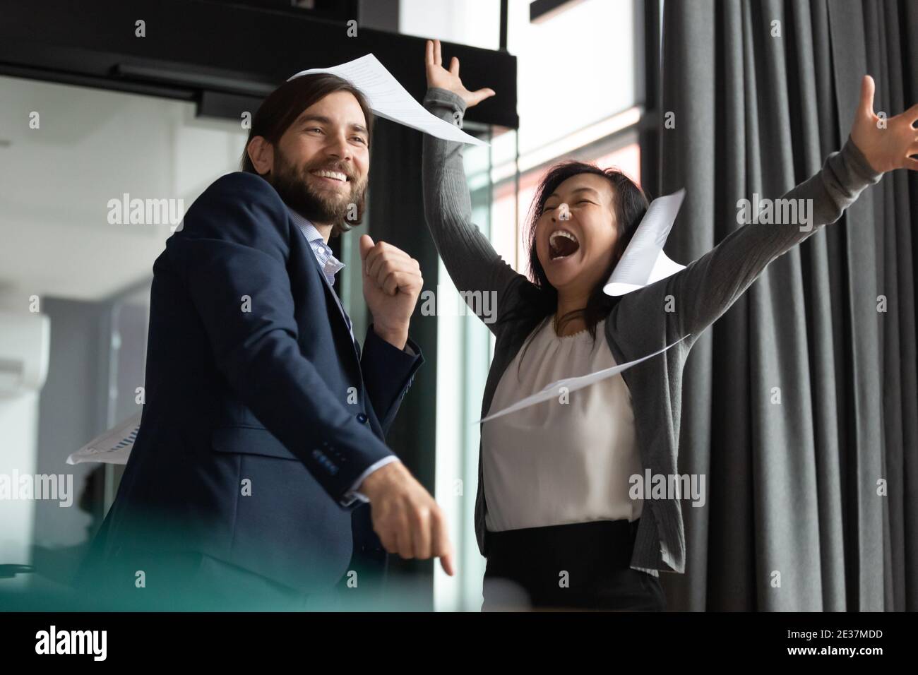 Überglücklich junge 30er Jahre Geschäftsmann feiert Erfolg mit reifen koreanischen Kollegen. Stockfoto