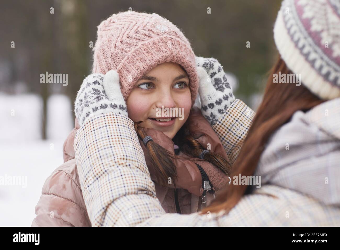 Nahaufnahme Porträt der fürsorglichen Mutter Anpassung Hut auf Queue Mädchen, während Sie gemeinsam im Winter im Freien spazieren gehen Stockfoto