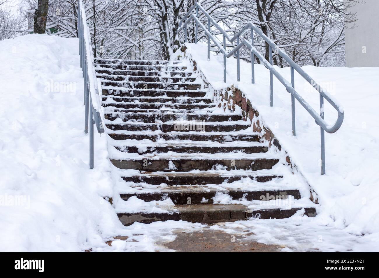 Die Betontreppe ist mit Schnee und Eis bedeckt und mit Sand bestreut. Stockfoto