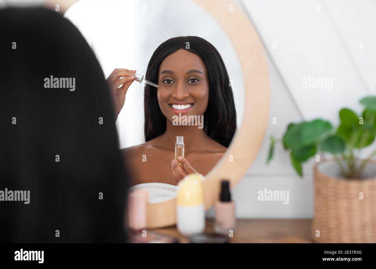 Kosmetik und Spa. Lächelnde Millennial african american Dame halten Pipette mit kosmetischem Öl Stockfoto