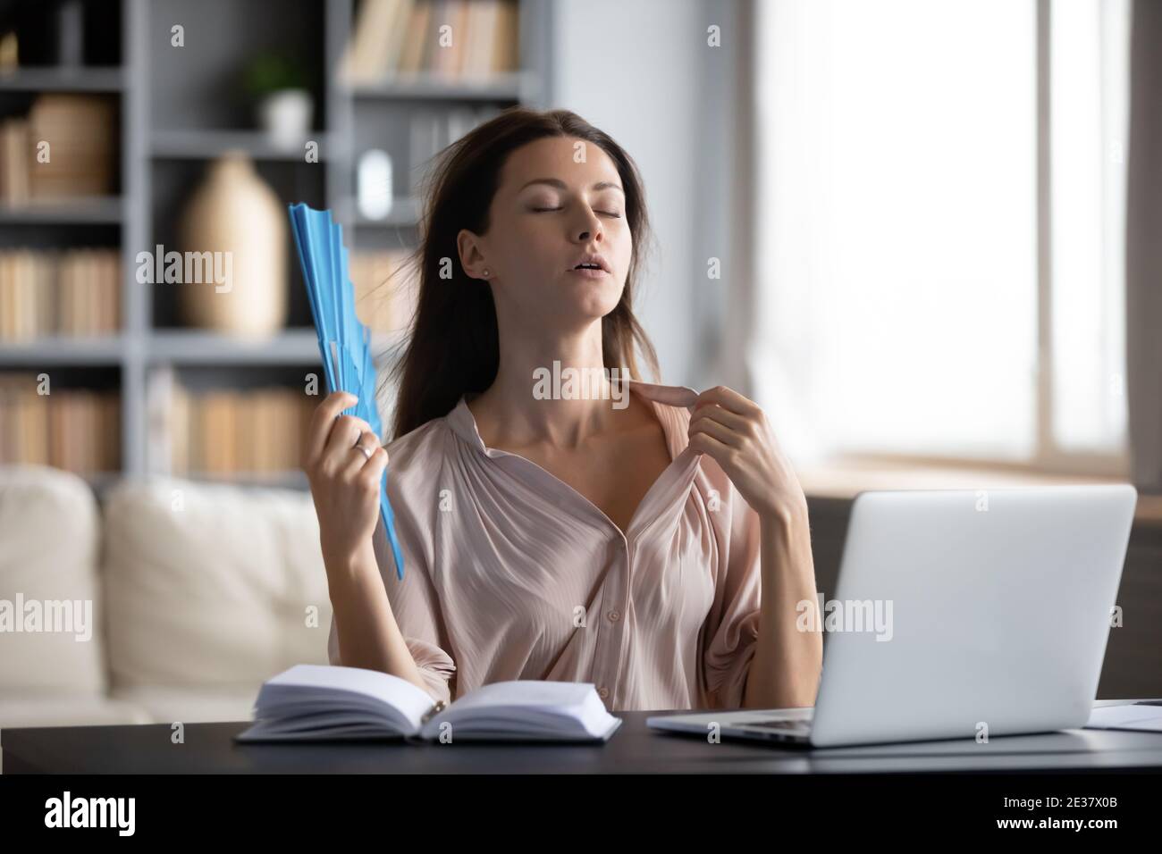 Nahaufnahme durstige Frau winkt Papierventilator, sitzen am Schreibtisch Stockfoto