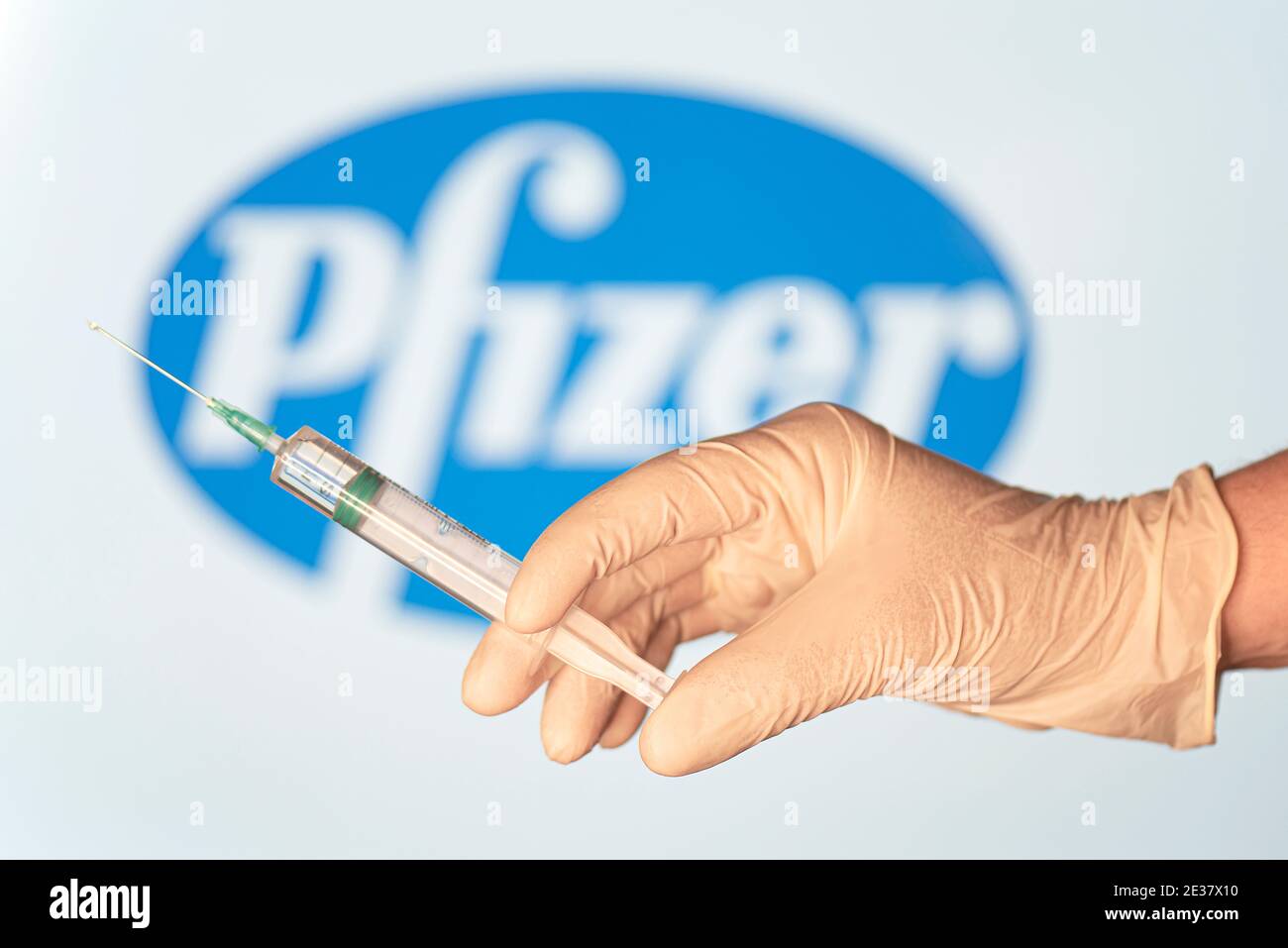 BERLIN - JAN 17: Konzept inszeniertes Bild. Coronavirus-Impfstoff von Pfizer, Arzthand mit Spritze und Impfstoff gegen Pfizer-Logo in Berlin, Janu Stockfoto