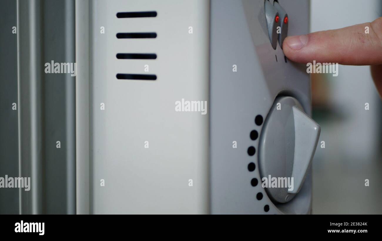 Bild mit einer Hand, die den Elektroerhitzer Thermostat setzt Zum Erwärmen eines kalten Raumes Stockfoto