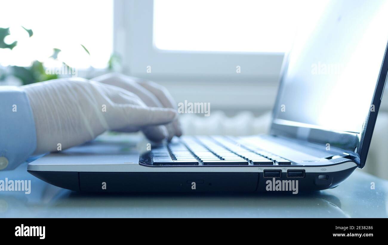 Nahaufnahme Bild mit Händen Tragen Schutzhandschuhe mit dem Laptop Tastatur Stockfoto