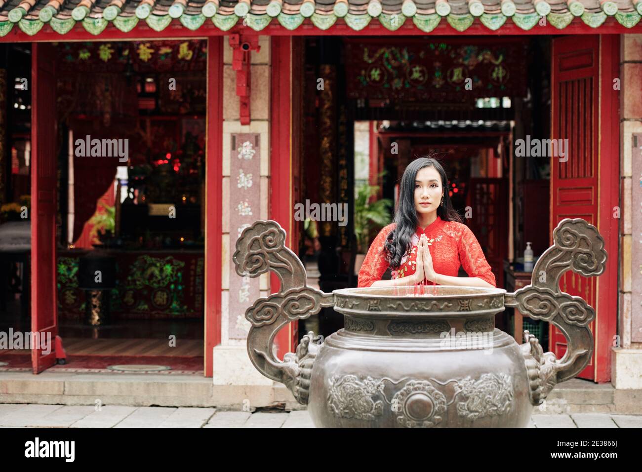 Schöne junge vietnamesische Frau beten bei Kupfer Urne mit Rauchen Stöcke im Tempel Stockfoto