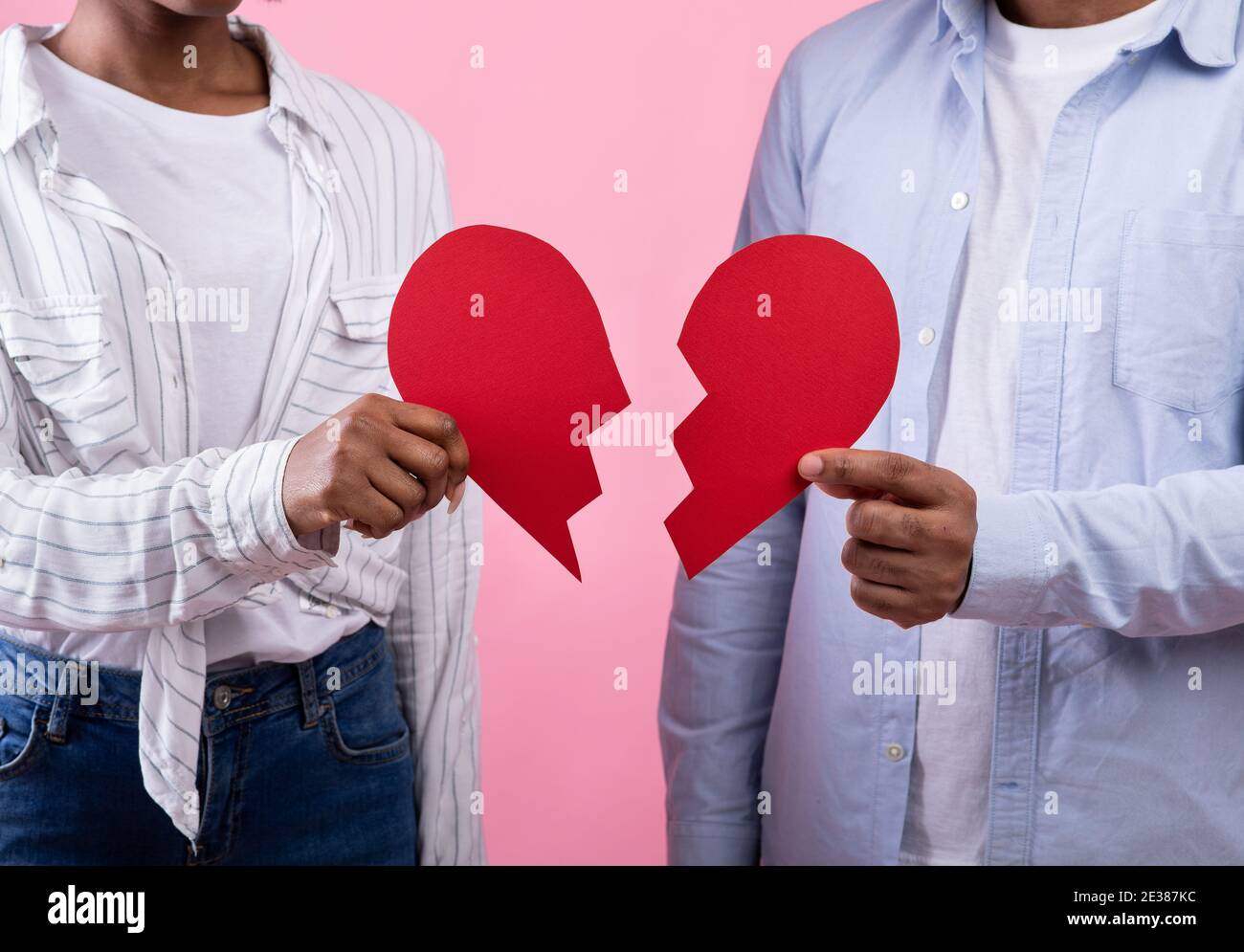 Scheidung, Trennung, Streit. Unbekanntes schwarzes Paar, das Hälften des gebrochenen Herzens über rosa Studiohintergrund hält Stockfoto