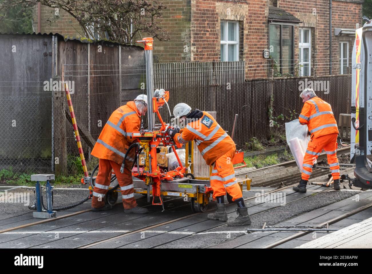 Arbeiter in orangefarbener Hochvisis-Kleidung, die an einer Bahnüberfahrt für AECOM und Resource Rail Ltd, Großbritannien, arbeiten Stockfoto