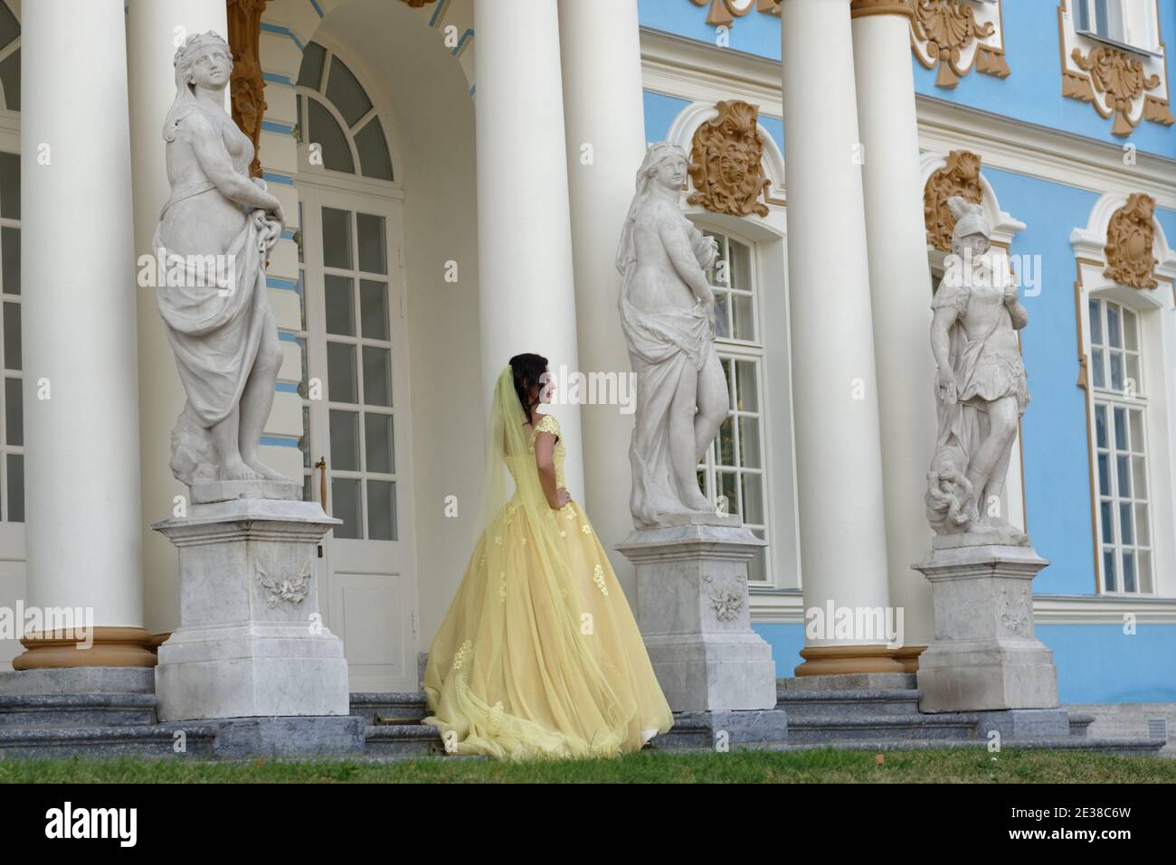 Braut in gelbem Kleid posiert vor dem Katharinenpalast in der Puschkin-Stadt bei St. Petersburg, Russland Stockfoto