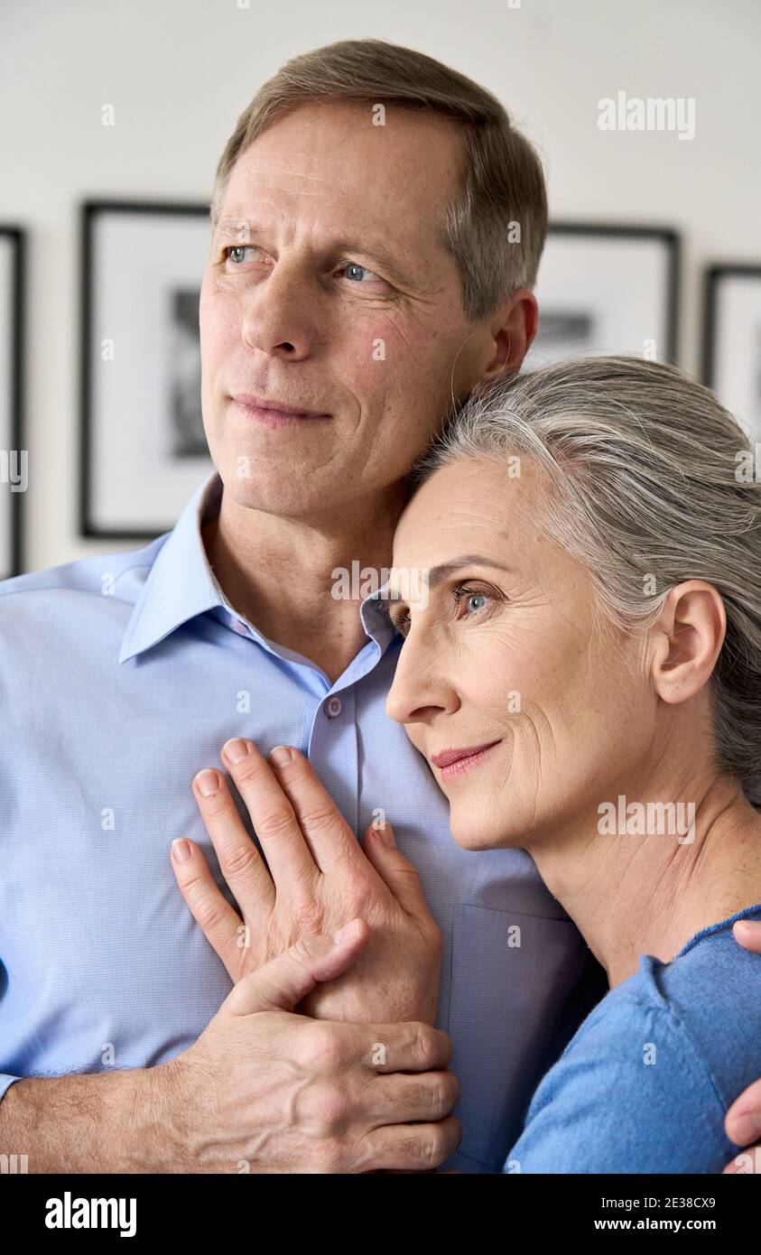Reifer Ehemann umarmt lächelnde Frau mittleren Alters, träumen von einer guten Zukunft. Stockfoto