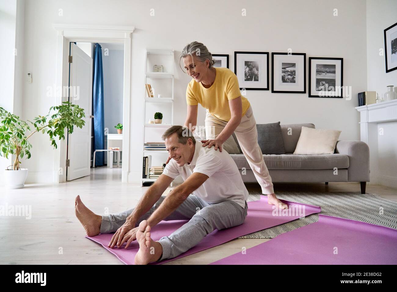 Fit aktive reife Frau hilft älteren Ehemann dabei Stretching-Übung zu Hause. Stockfoto