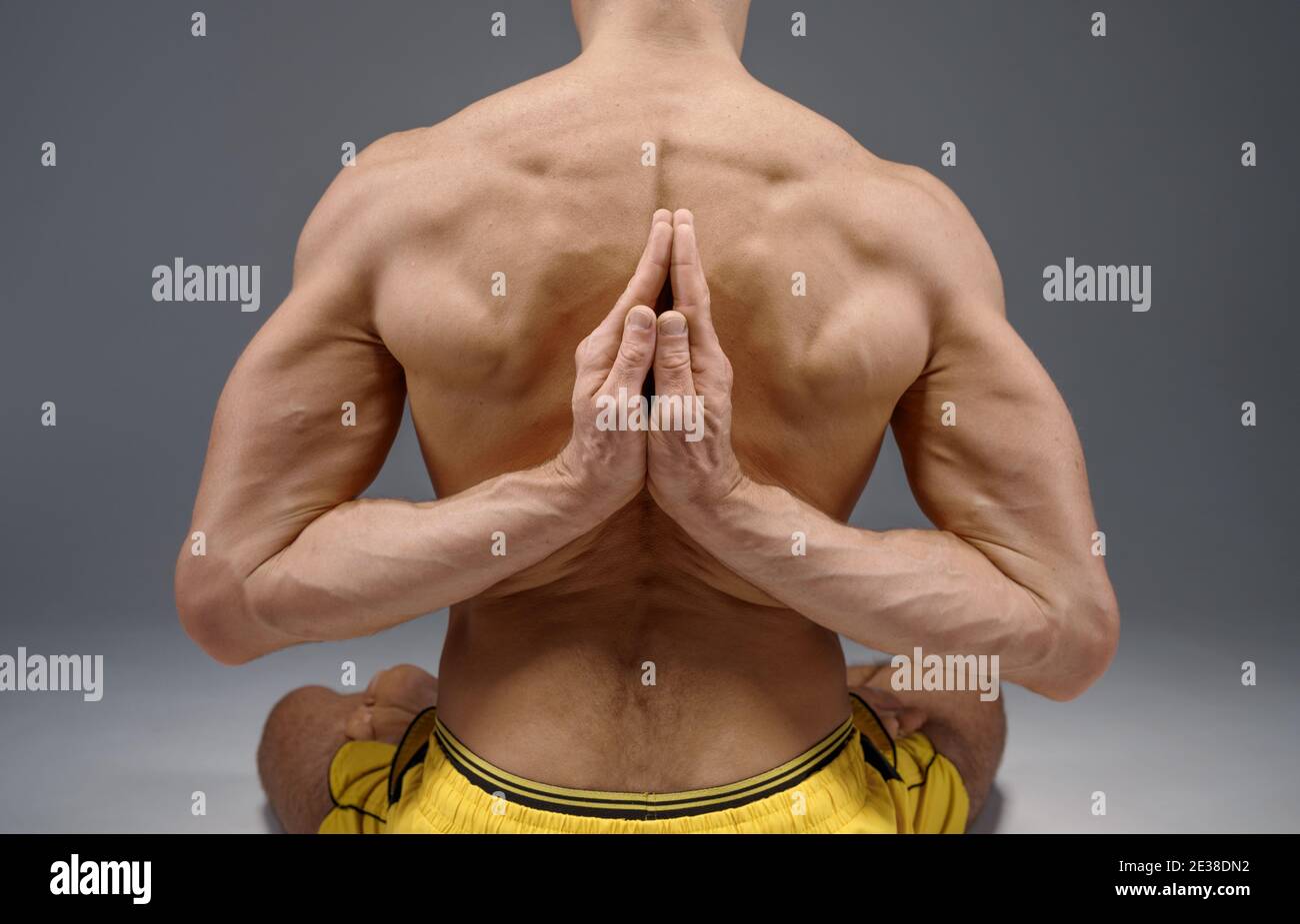 Yoga sitzt mit den Händen hinter seinem Rücken Stockfoto
