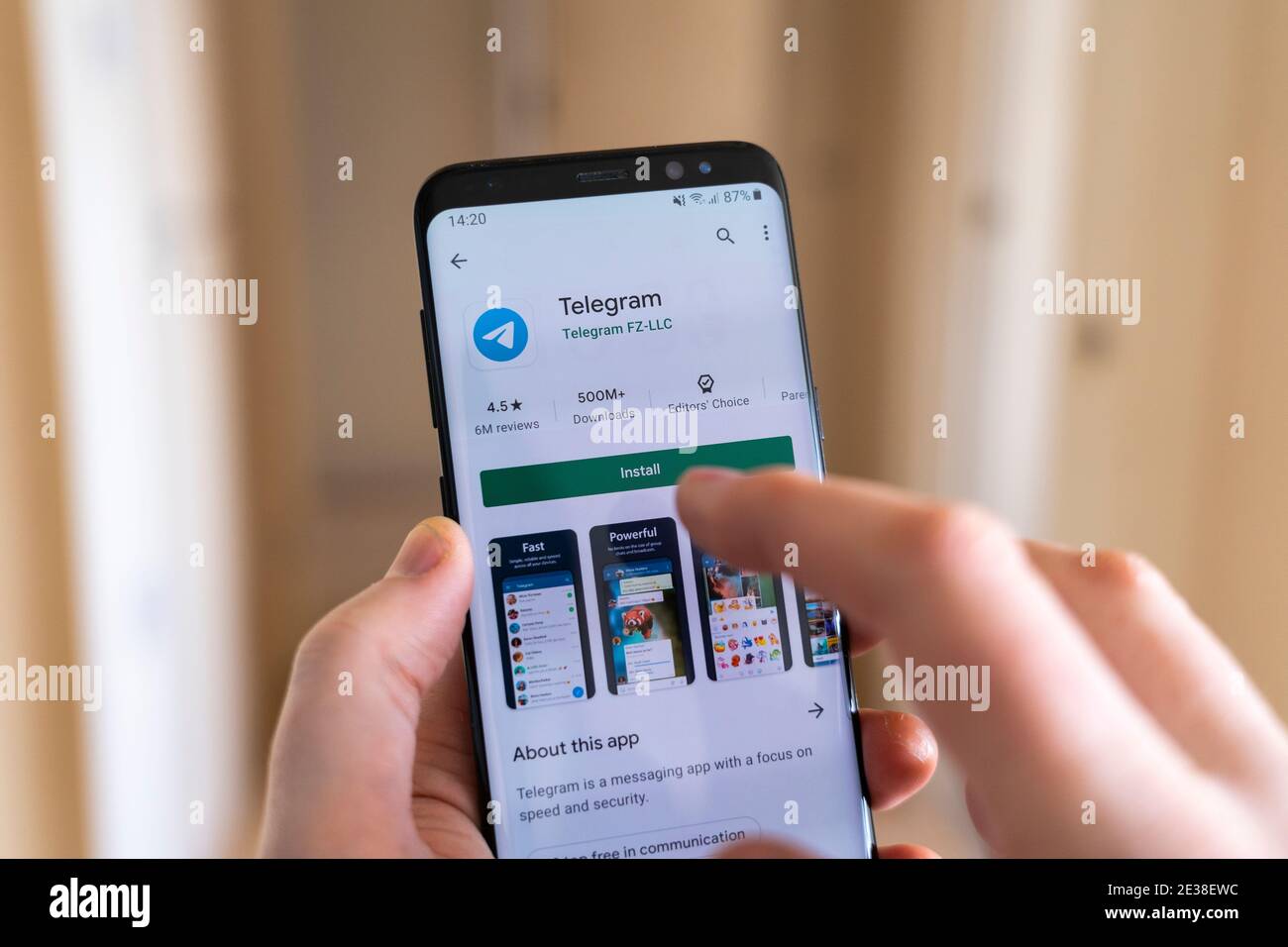 Eine Hand, die ein Smartphone mit einem Finger hält und den auswählt Installieren Sie die Schaltfläche auf dem Google Play Store für das Video Chat- und Messaging-App Telegram Stockfoto