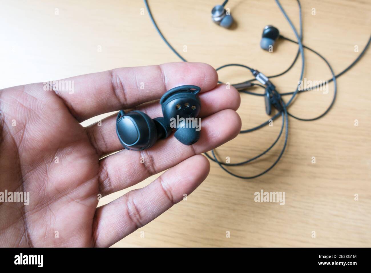 Asiatische Männer halten Ohrstöpsel drahtlose Technologie über kabelgebundene Kopfhörer Als Trendtechnologie Stockfoto
