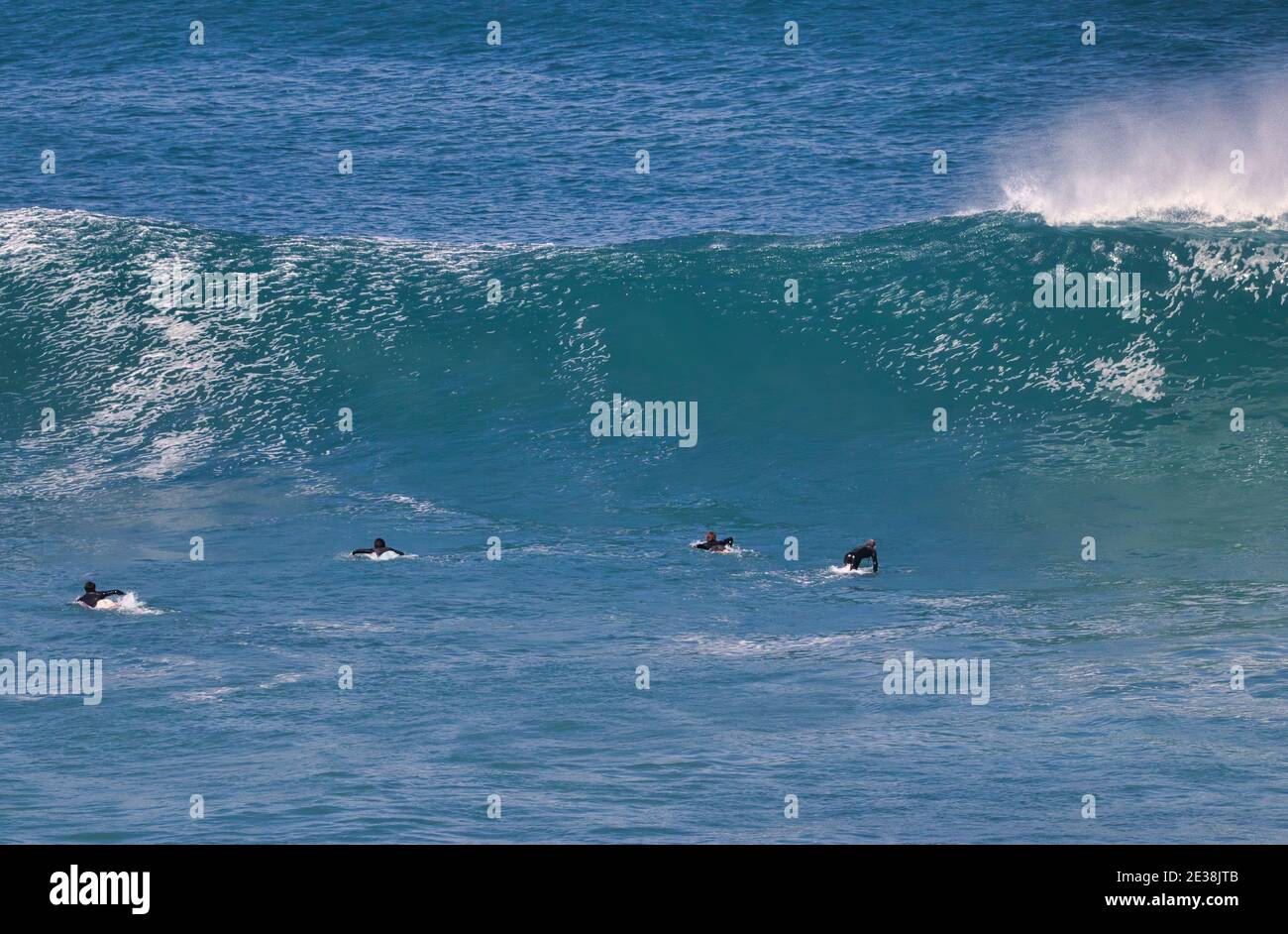 Sehr entfernter Surfer, der auf eine Kurve wartet, um eine Welle zu reiten. Stockfoto