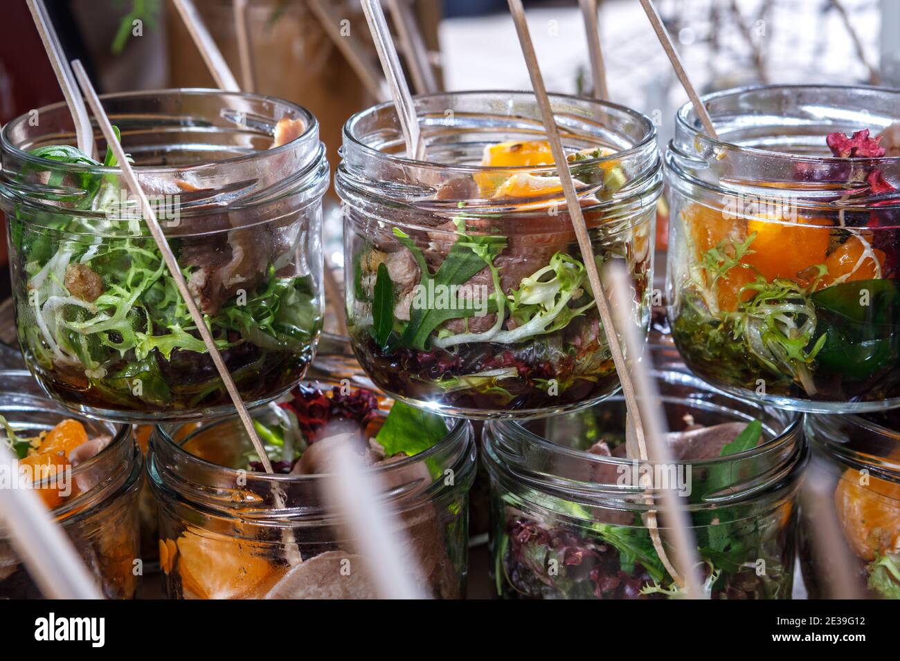 Cocktail aus Rucola Blatt Fleisch und Obst in Gläsern mit Holzgabeln. Umweltfreundliche Gerichte. Das Konzept der gesunden Ernährung Stockfoto