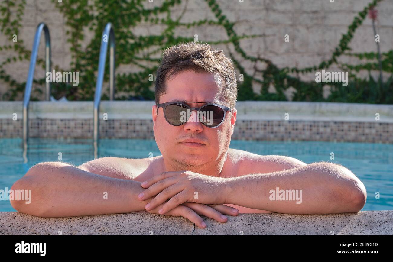 Portrait eines Mannes am Pool mit Sonnenbrillen Blick auf die Kamera Stockfoto