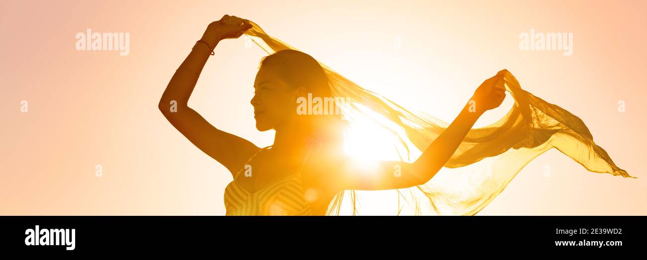 Schöne Frau glücklich frei in Sonnenuntergang glühen winkende Schal im Wind tanzen in Sonne Panorama-Banner. Silhouette feminine Dame Freiheit für Wellness und Stockfoto