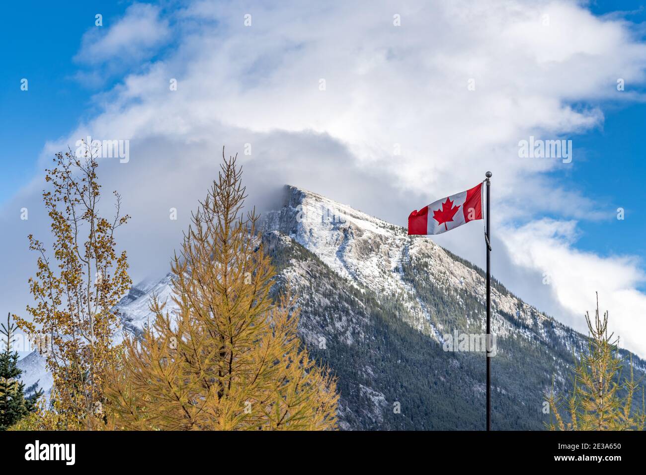 National Flag of Canada mit Mount Rundle Bergkette an einem verschneiten sonnigen Tag. Banff National Park, Canadian Rockies. Stockfoto