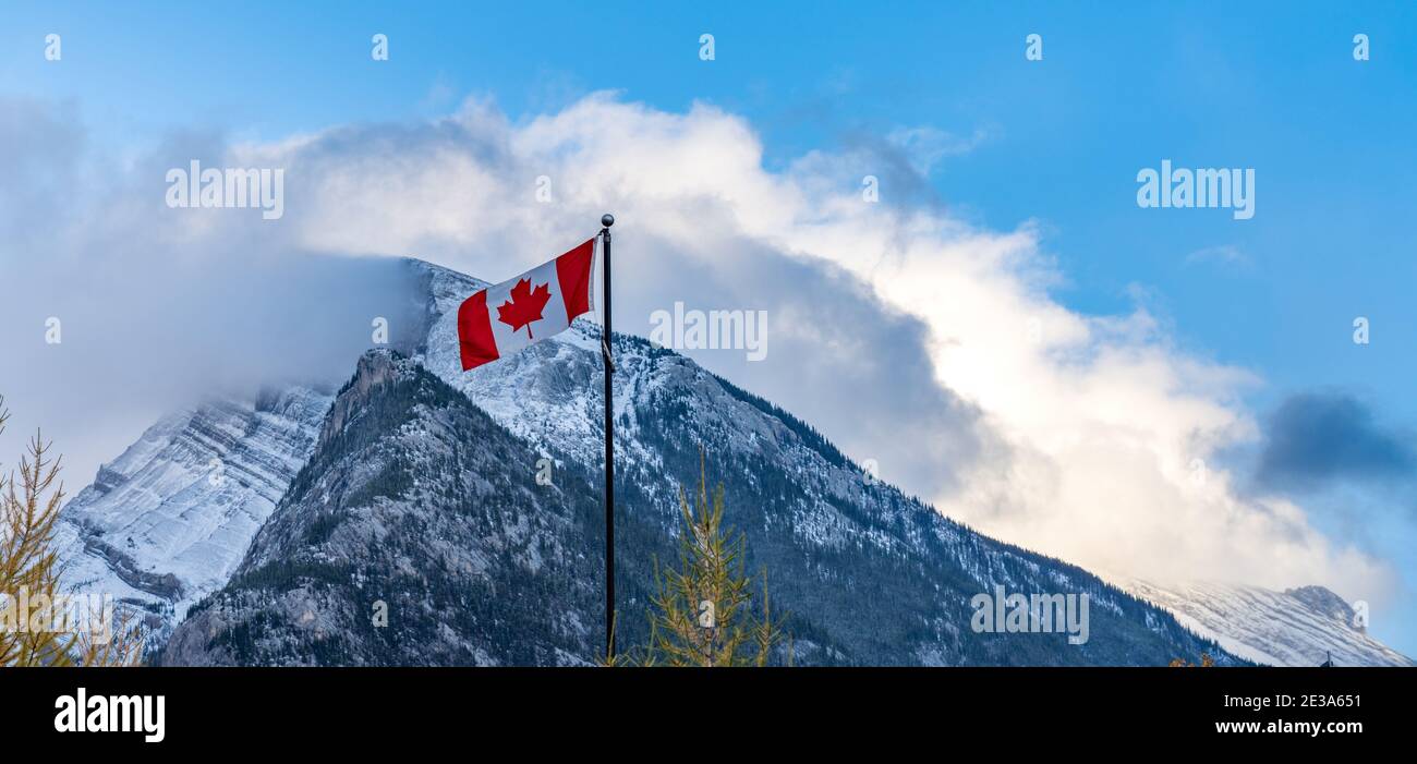 National Flag of Canada mit Mount Rundle Bergkette an einem verschneiten sonnigen Tag. Banff National Park, Canadian Rockies. Stockfoto