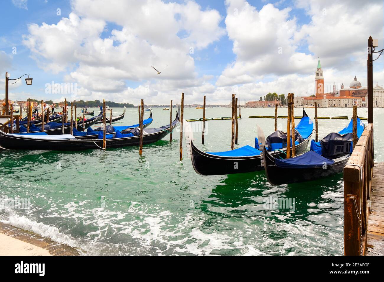 Gondeln entlang des Canale Grande mit der Riva di Schiavoni und der Kirche und der Insel San Giorgio Maggiore in der Ferne in Venedig, Italien sichtbar. Stockfoto Gondeln entlang des Canale Grande mit der Riva di Schiavoni und der Kirche und der Insel San Giorgio Maggiore in der Ferne in Venedig, Italien sichtbar. Stockfoto
