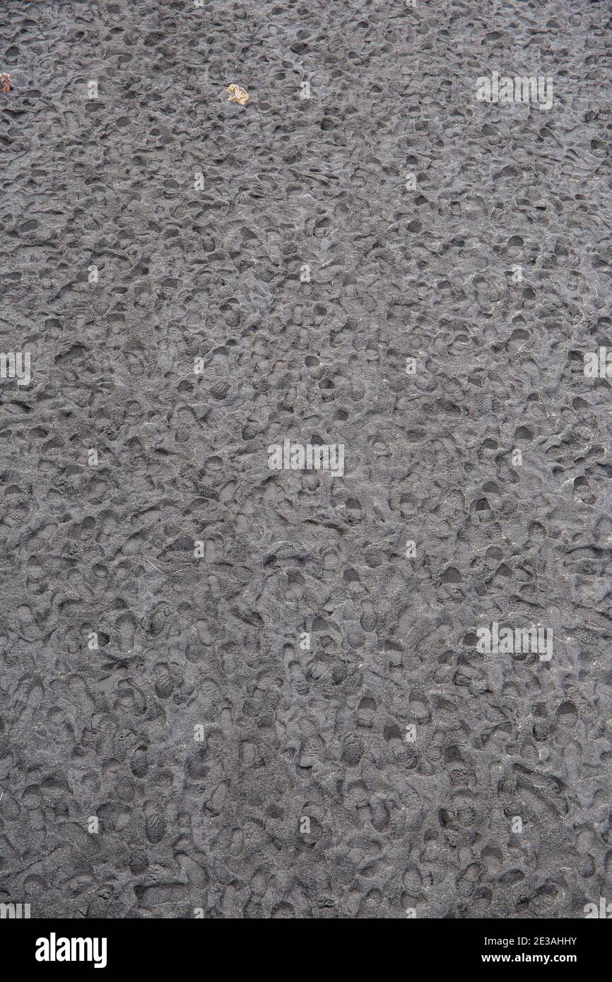 Muster von Spuren in schwarzem Sand Stockfoto