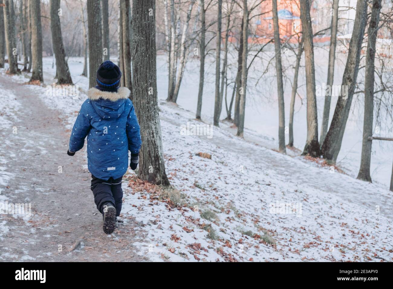 Junge geht durch den Winterwald. Reisen Sie in kalte Länder. Ein Kind geht auf einem Weg durch den Wald. Wandern in der Natur Stockfoto