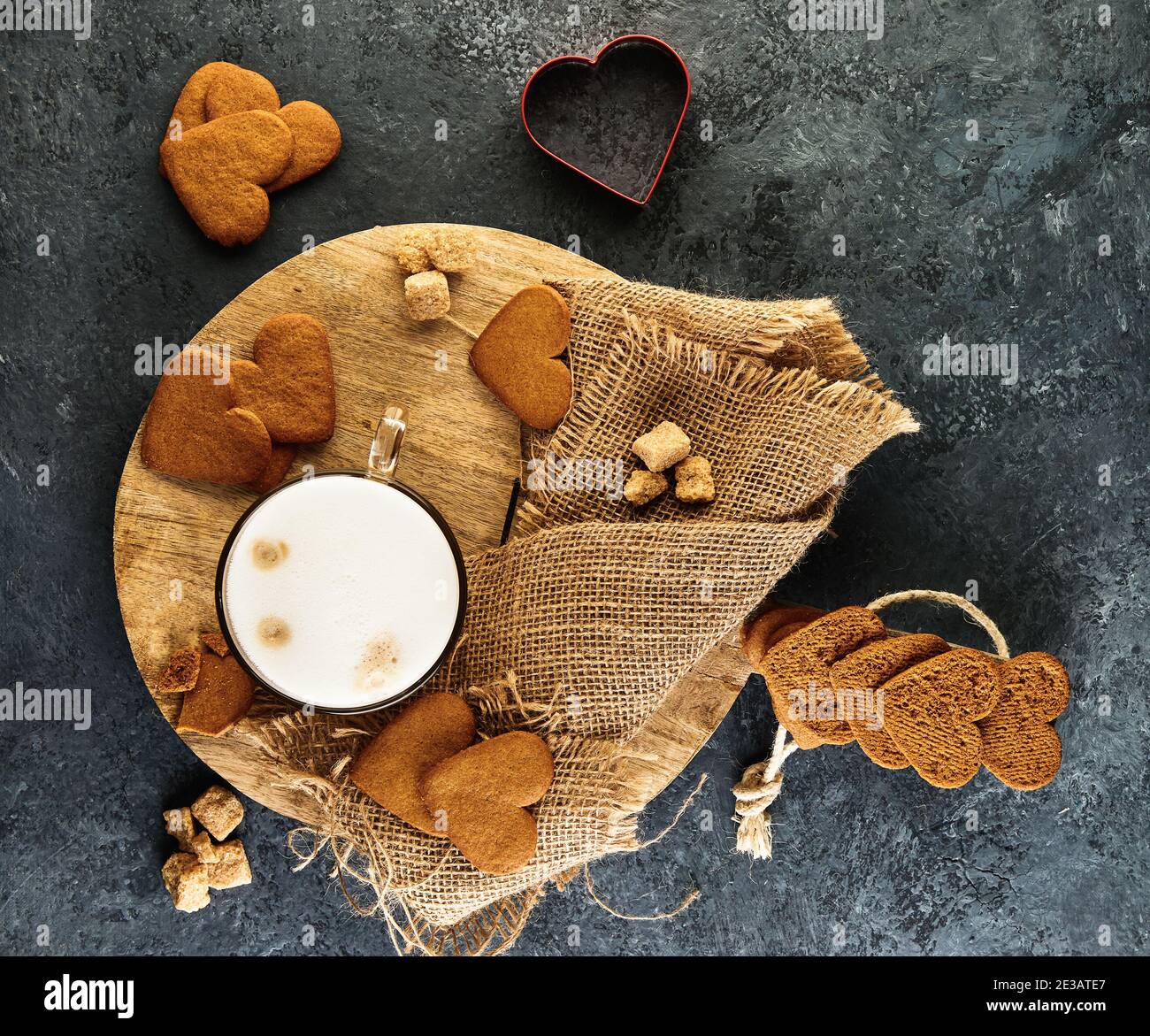 Herzförmige Lebkuchenkekse mit einer Tasse Cappuccino Auf einem Holzbrett Stockfoto