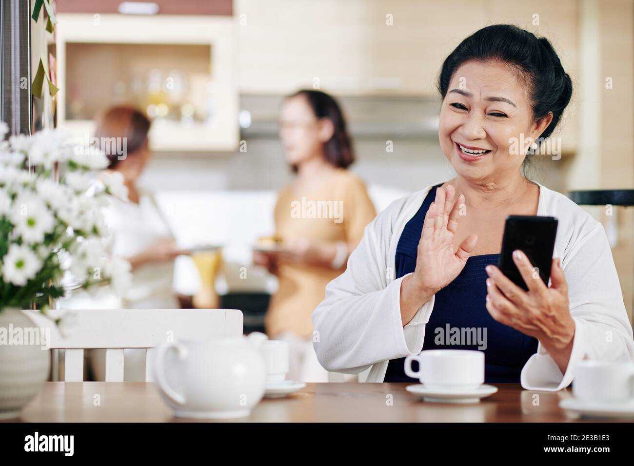 Porträt einer glücklichen älteren vietnamesischen Frau winken mit der Hand, wenn Video ruft ihre Freunde oder Familienmitglieder an Stockfoto