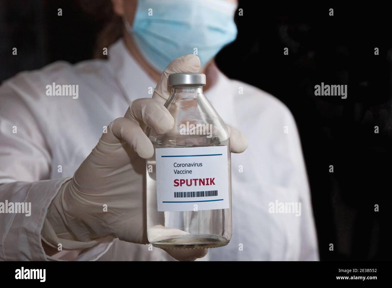 Krasnodar, Russland - 12. Januar 2021: Sputnik Impfstoffflasche auf dem Hintergrund eines Arztes in einer Maske und weißem Mantel Stockfoto
