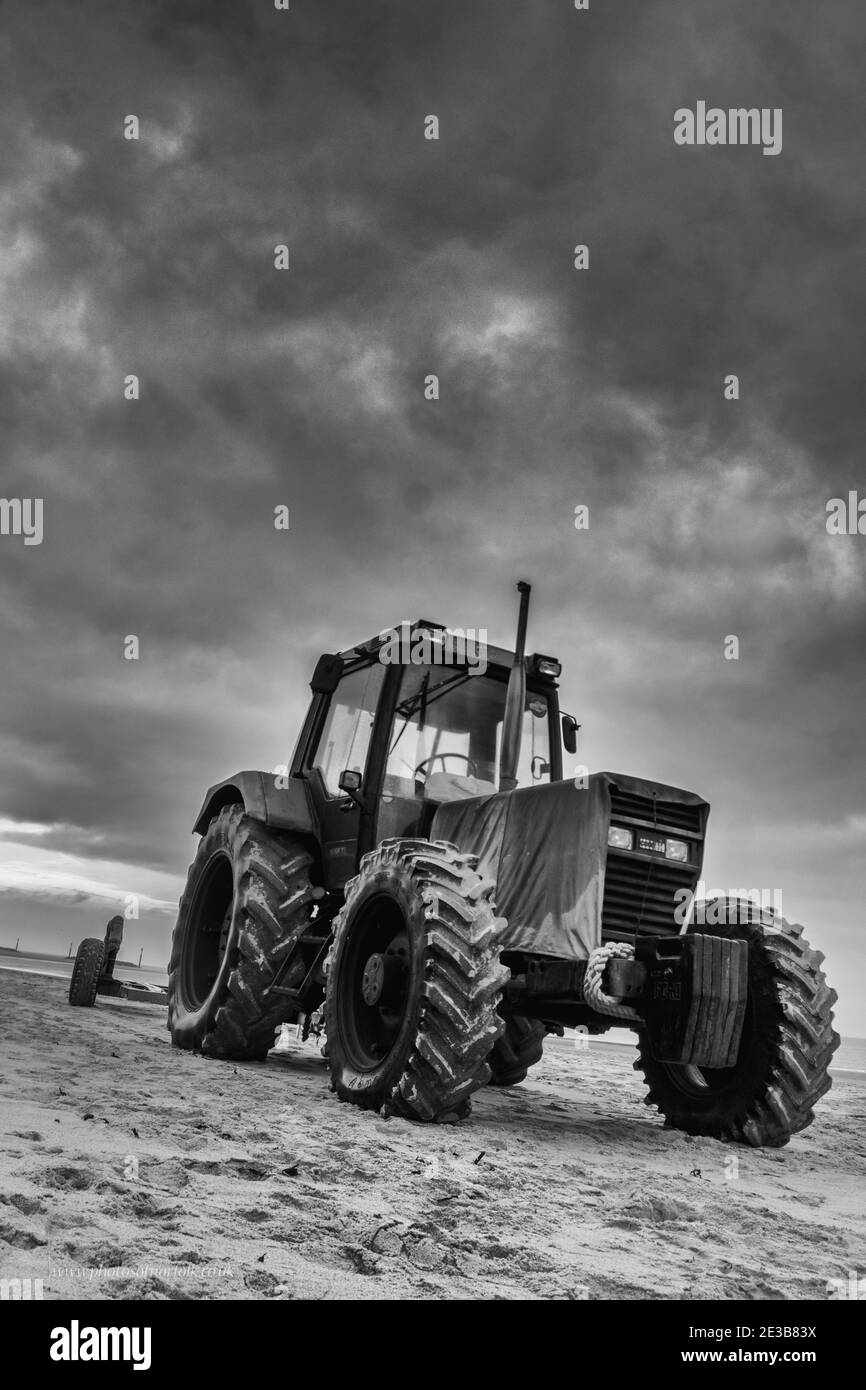 Vertikale Graustufenaufnahme eines Traktors und ein trübes Dunkel Himmel Stockfoto