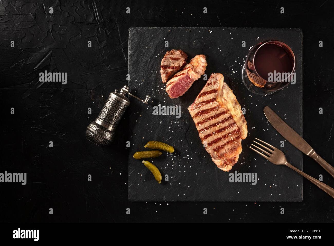 Gegrilltes Rindersteak mit Rotwein, mittelselten, über Kopf geschossen auf dunklem Hintergrund mit Platz für Text Stockfoto