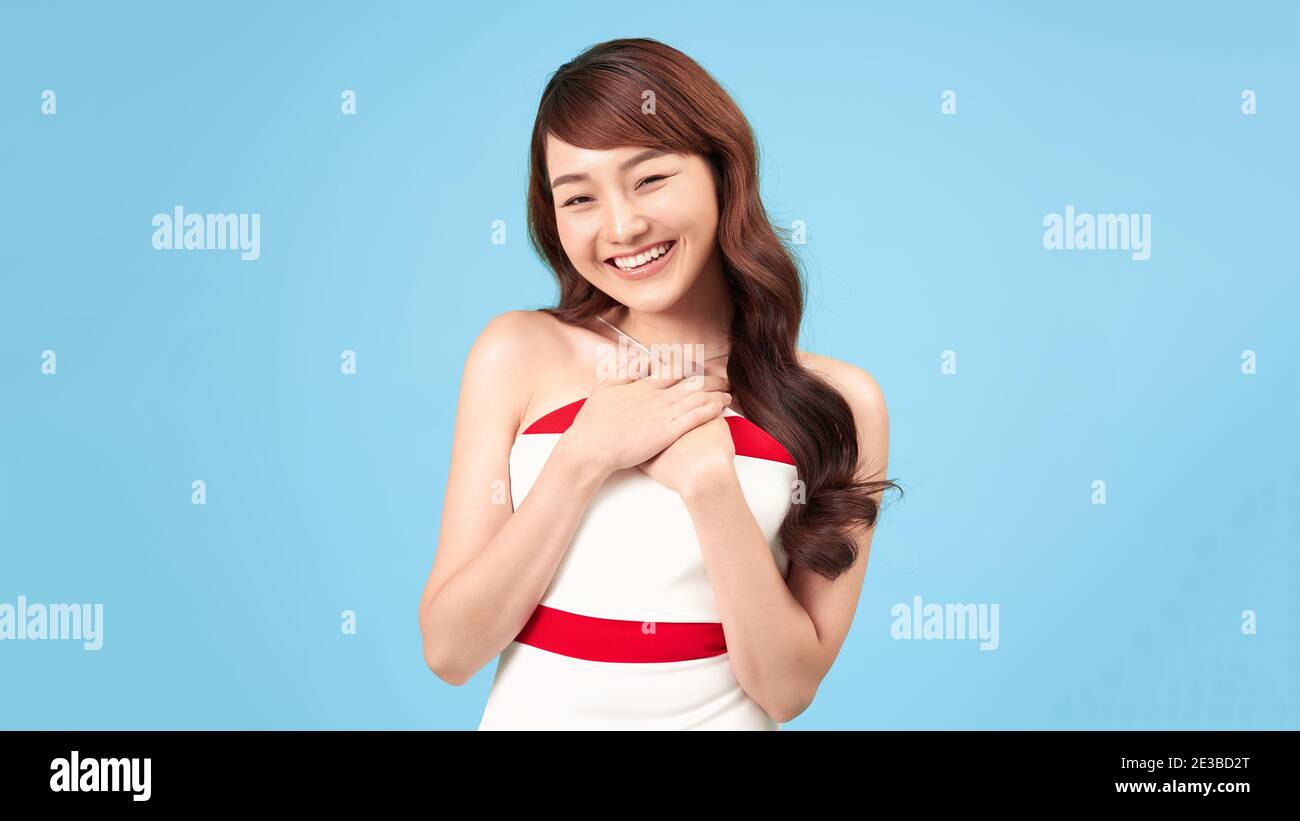 Lächelnde asiatische Frau hält die Hände in der Nähe des Halses Stockfoto