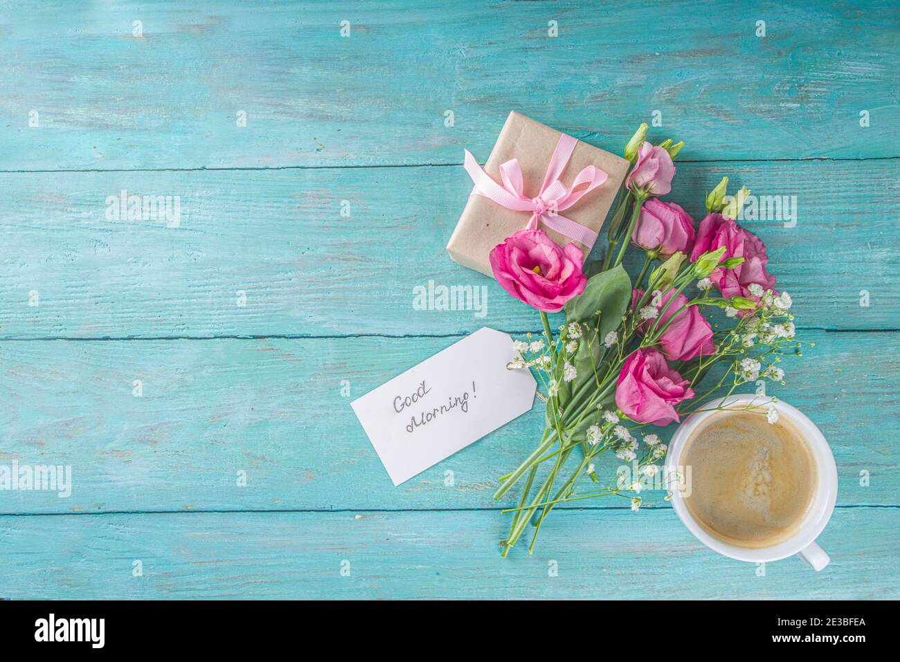 Blumenstrauß des Frühlings, Sommerblumen, Kaffeetasse und Noten Guten Morgen, haben Sie einen schönen Tag auf blauem Holztisch. Sommer Morgen schönes Frühstück, greeti Stockfoto