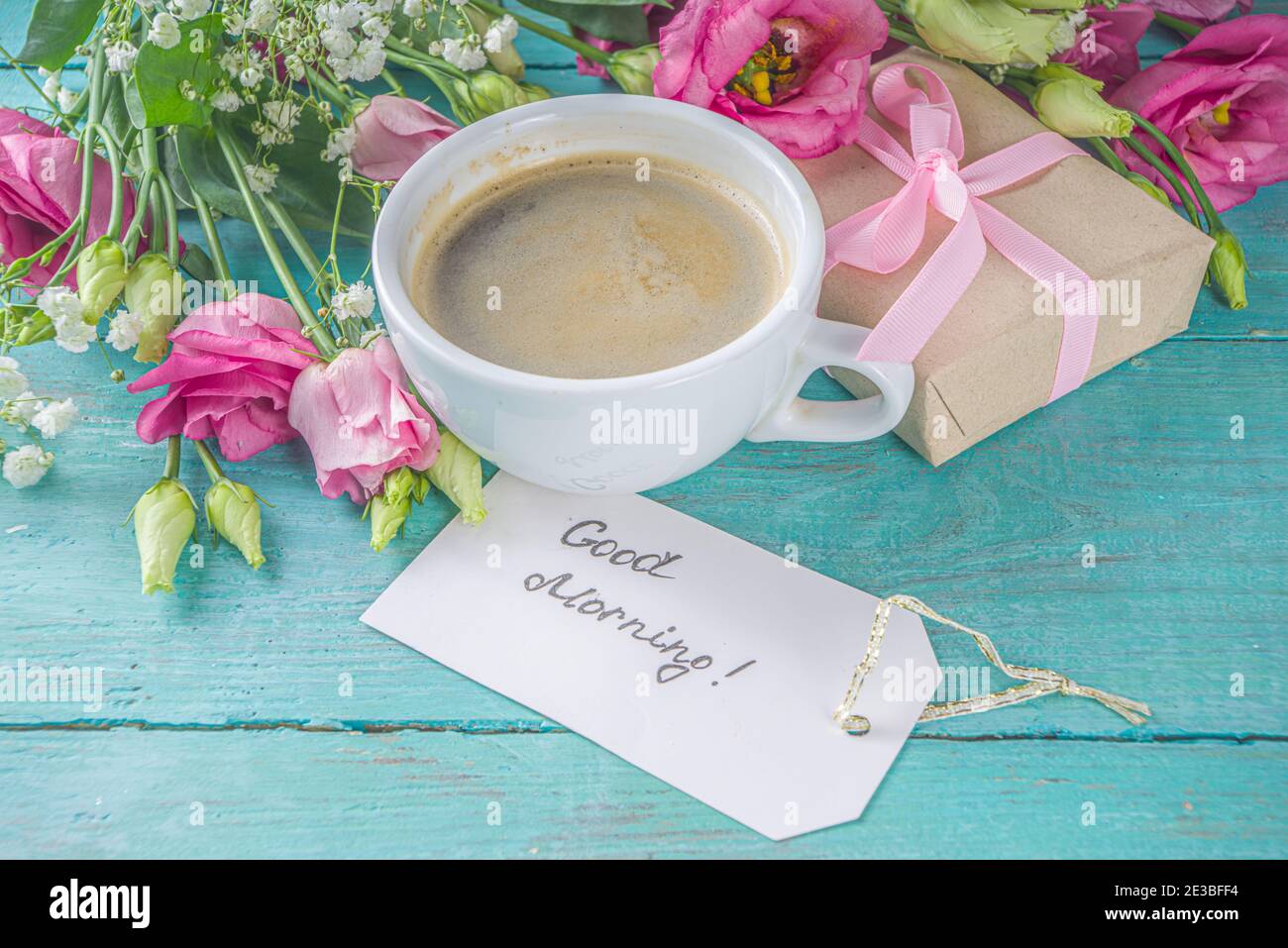 Blumenstrauß des Frühlings, Sommerblumen, Kaffeetasse und Noten Guten Morgen, haben Sie einen schönen Tag auf blauem Holztisch. Sommer Morgen schönes Frühstück, greeti Stockfoto