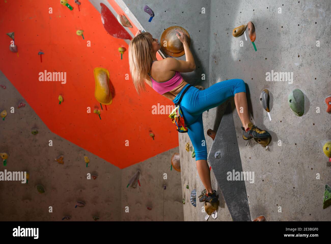 Junge Klettererin Bouldern in der Kletterhalle. Extreme Sport und Indoor Climbing Konzept Stockfoto