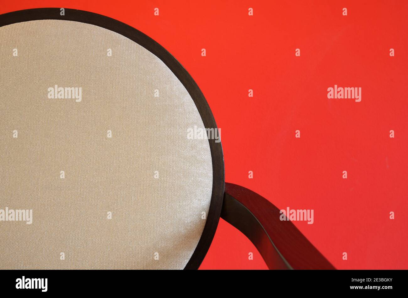 Abstrakt minimalistisches Detail des modernen Essstuhls mit runder Stuhl-Rückenlehne Fotografiert gegen eine Rote Mauer Stockfoto