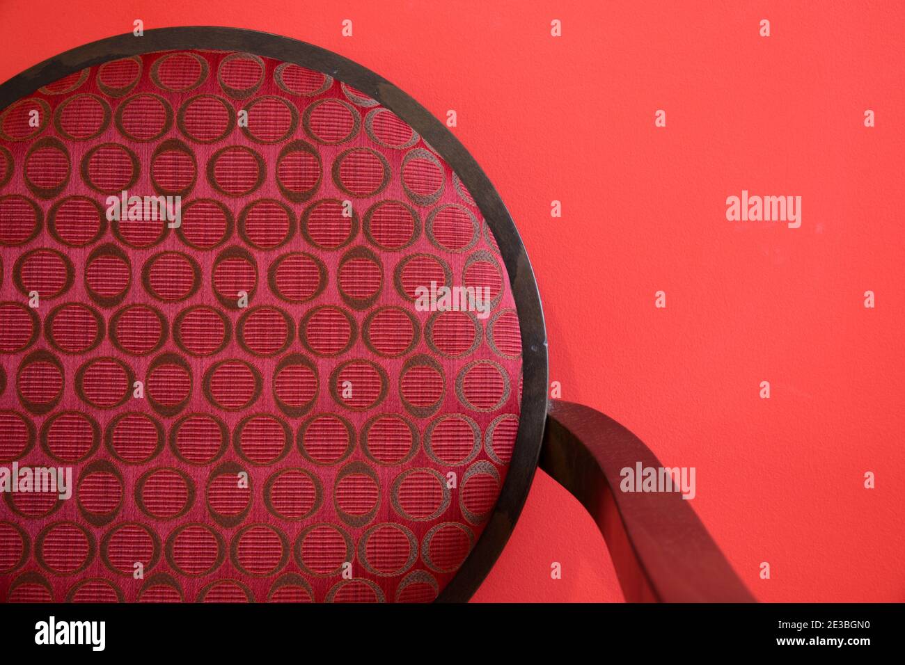 Abstrakt minimalistisches Detail des modernen Essstuhls mit runder Stuhl-Rückenlehne Fotografiert gegen eine Rote Mauer Stockfoto